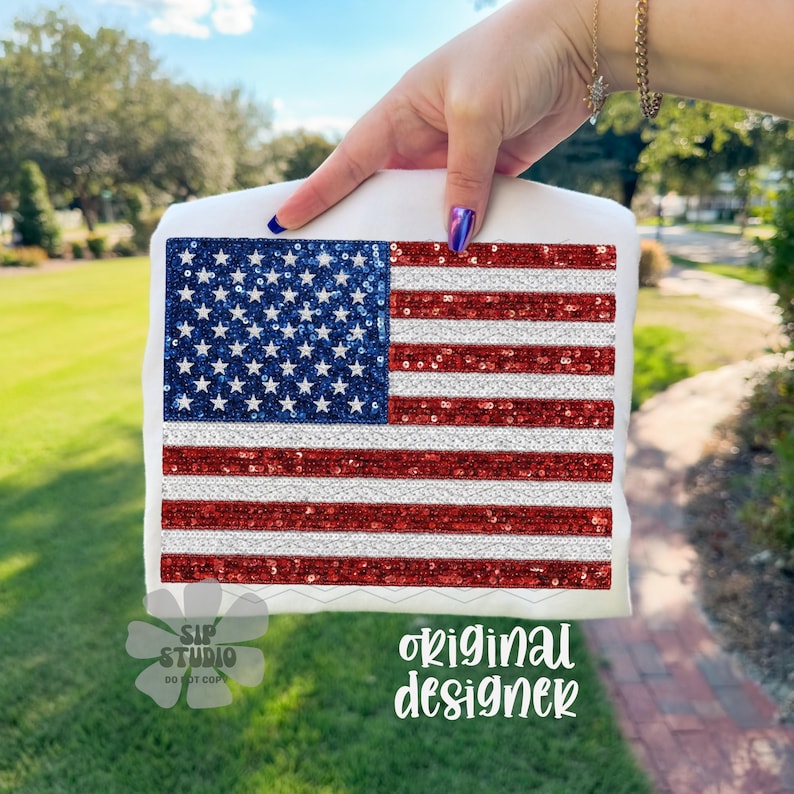 May include: A white square item with a sequined American flag design. The flag features a blue sequined field with white stars and red and white striped sequins. The text "original designer" is visible in the image.