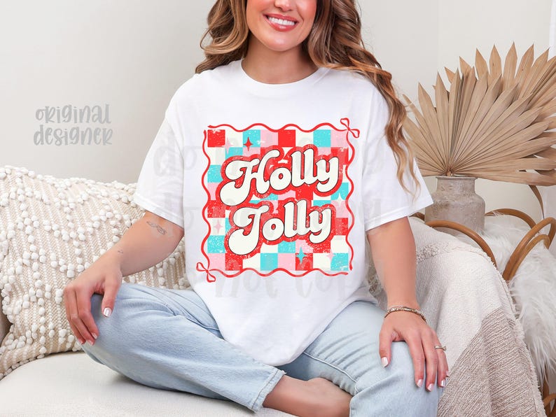 May include: White t-shirt with a retro design that says "Holly Jolly" in red and white, set against a red, pink, and blue checkered background. The shirt has a vintage, distressed look.
