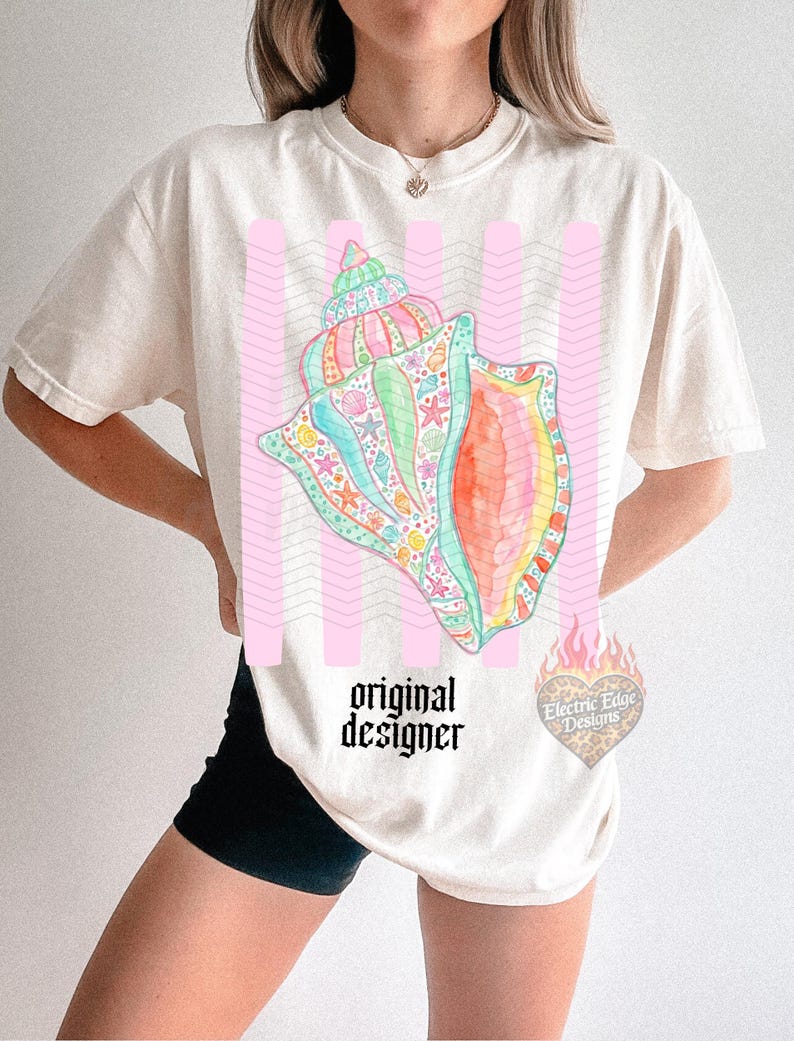 May include: Cream-colored t-shirt featuring a colorful seashell design with pink vertical stripes. The seashell is detailed with various sea creatures and vibrant colors. The text "original designer" is printed below the seashell.