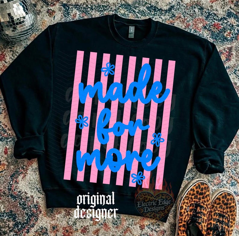 May include: Black sweatshirt with the text "made for more" in blue script over pink vertical stripes. The design includes small blue flower accents. The words "original designer" are at the bottom.