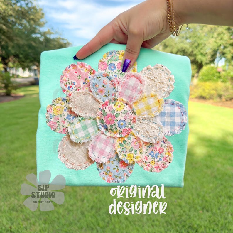 Comfort Colors Mockup. May include: A light turquoise t-shirt featuring a large, appliqued flower design. The flower is composed of various fabric scraps in floral and gingham patterns, with a frayed edge. The text "original designer" is visible.