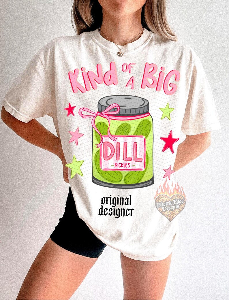 May include: Cream-colored t-shirt with a graphic of a pickle jar labeled "DILL PICKLES." The text "Kind of a BIG" is above the jar in pink, with star accents. The words "original designer" are below the jar.