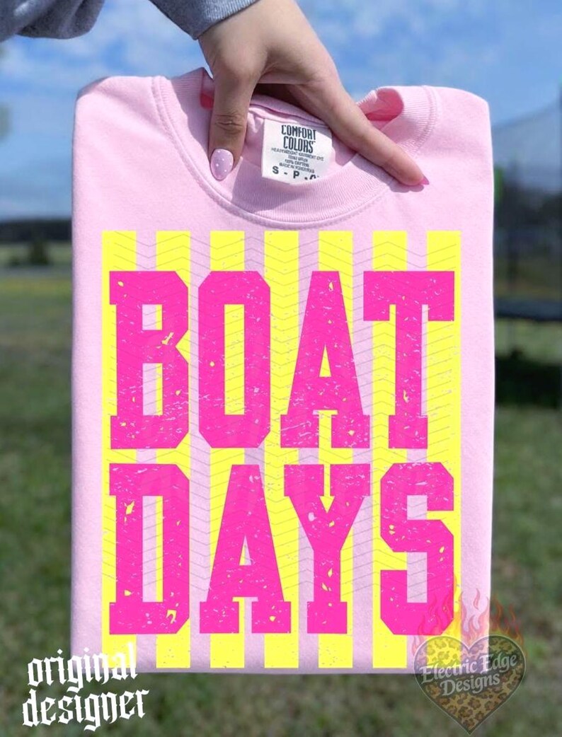 Może przedstawiać: R&oacute;żowa bluza z napisem "BOAT DAYS" dużymi, wytartymi, neonowo-r&oacute;żowymi literami na ż&oacute;łtym tle w paski. Słowa "original designer" znajdują się w lewym dolnym rogu.
