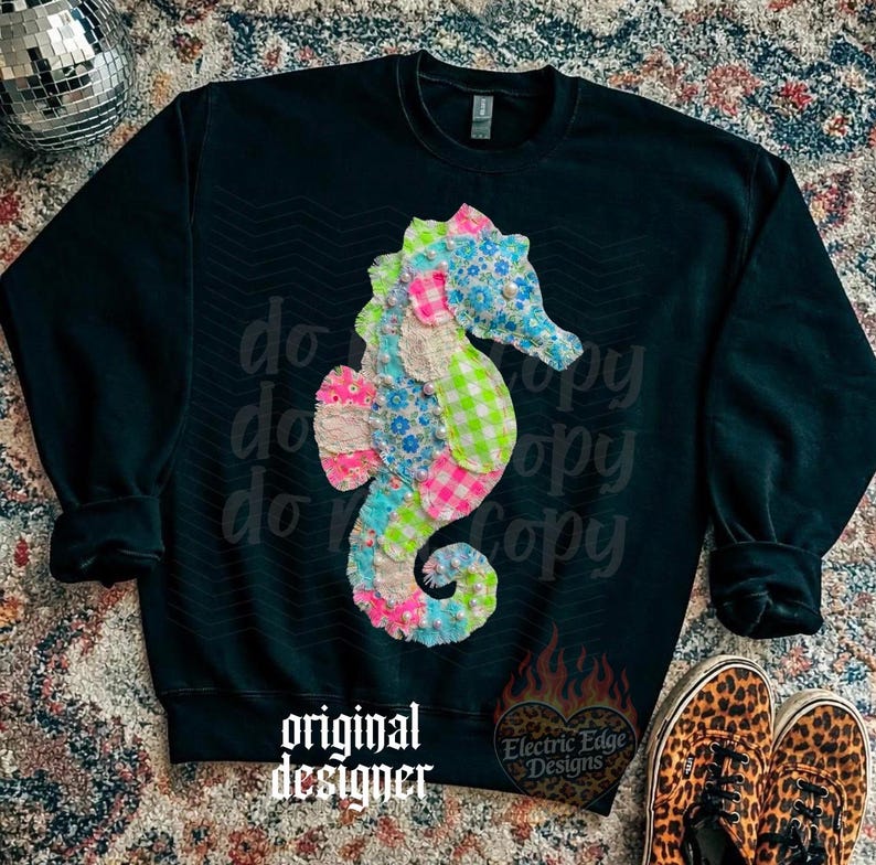 May include: Black sweatshirt featuring a colorful seahorse design made of floral, gingham, and solid fabric patches. The words "original designer" are printed at the bottom. The design includes the text "do copy" repeated diagonally.