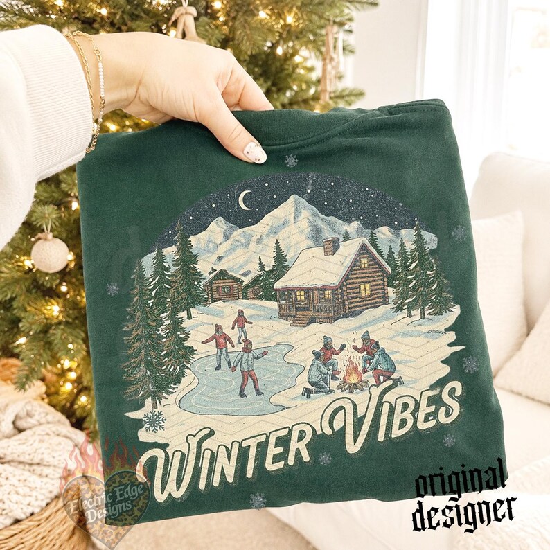 May include: A dark green sweatshirt featuring a graphic print of a snowy mountain landscape with log cabins, people ice skating, and a campfire. The text "WINTER VIBES" is printed in a cream-colored script font at the bottom of the design.
