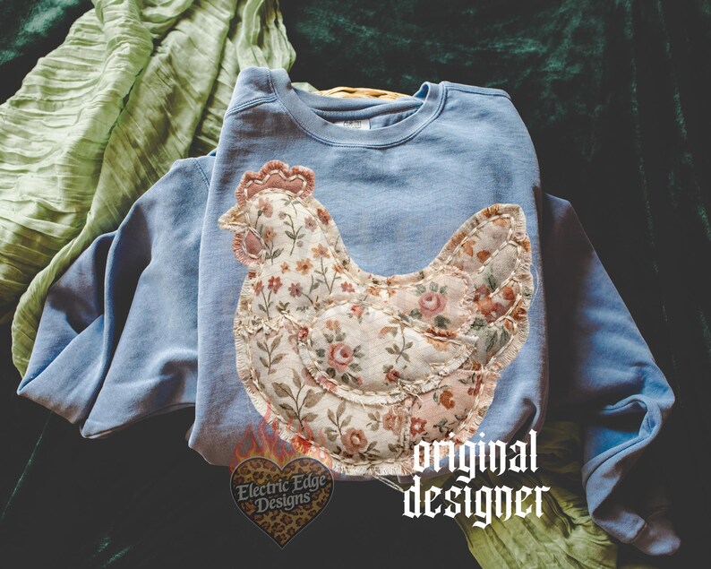 May include: A light blue sweatshirt with a floral chicken applique. The chicken design features a patchwork style with a variety of floral patterns in shades of pink, cream, and green. The text "original designer" is visible.