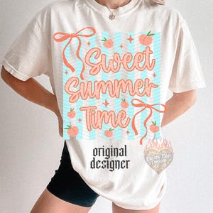 May include: Cream-colored t-shirt with a "Sweet Summer Time" graphic in coral and light blue. The design includes peaches and ribbons. The words "original designer" are printed below the graphic.