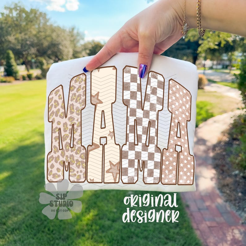May include: White t-shirt with the word "MAMA" in large, decorative letters. The letters feature various patterns, including leopard print, chevron, checkered, and star designs. The words "SIP STUDIO DO NOT COPY" and "original designer" are also visible.