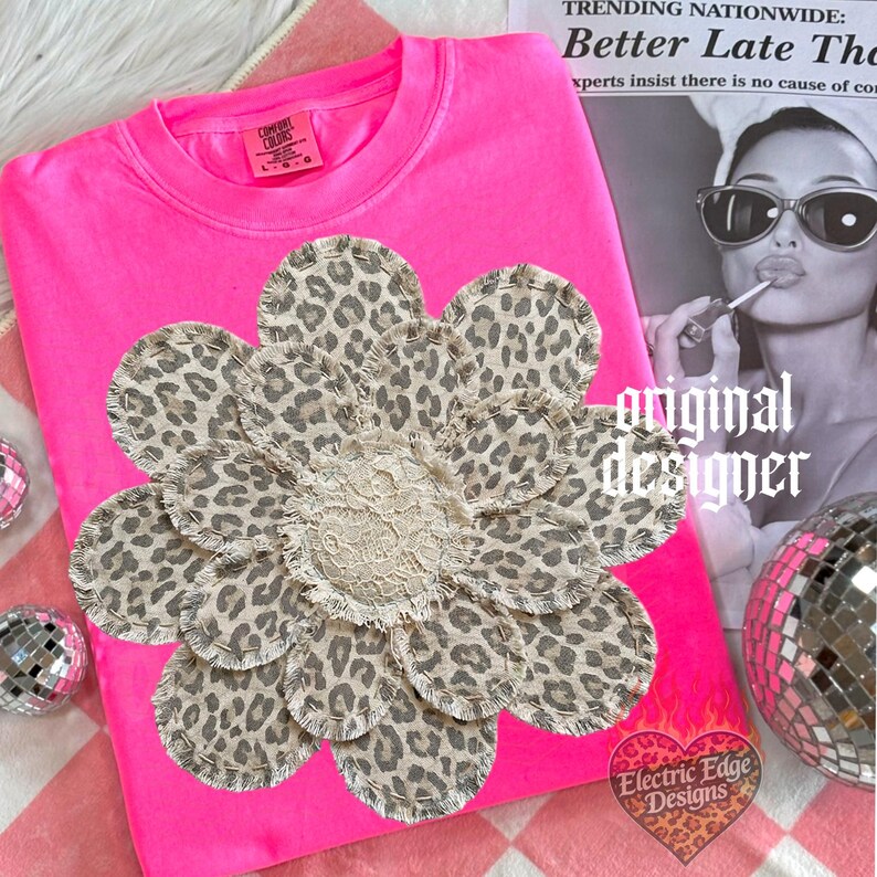 May include: A hot pink sweatshirt with a large flower applique. The flower has leopard print petals and a cream-colored lace center. The words "original designer" are printed on the image.