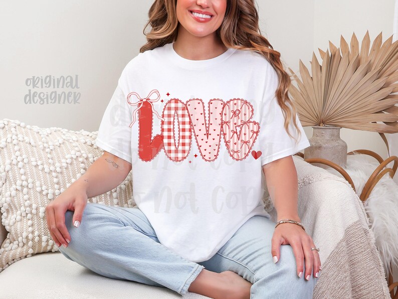 May include: White t-shirt with the word "LOVE" in red, featuring various patterns like gingham, hearts, and bows. The shirt has a casual fit and is suitable for Valentine's Day or expressing affection.