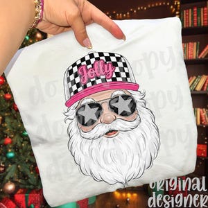 May include: White pillow with a graphic of Santa Claus wearing a checkered hat with the word "Jolly" and star-shaped sunglasses. The Santa has a long white beard and mustache. The pillow is held by a person.