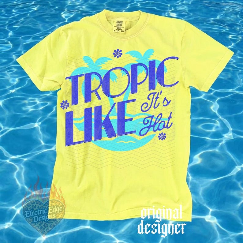 May include: A bright yellow short-sleeve t-shirt featuring a blue graphic print with the text TROPIC LIKE It's Hot. The design includes stylized palm trees, small flower icons, and wavy line patterns. The shirt has a crew neckline and a standard fit.