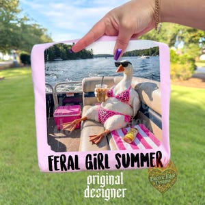 K&ouml;nnte beinhalten: Ein rosa gerahmtes Bild mit einer Gans mit Sonnenbrille und einem pinkfarbenen Leoparden-Bikini, die einen Eiskaffee auf einem Boot h&auml;lt. Der Text "FERAL GIRL SUMMER" und "original designer" ist auf dem Bild zu sehen.