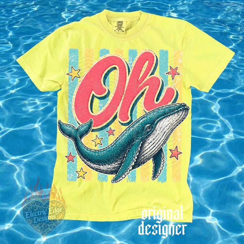 May include: Yellow t-shirt with a graphic of a blue whale and the word "Oh" in red. The design includes stars and vertical stripes in blue, yellow, and pink. The shirt has a crew neck and short sleeves.