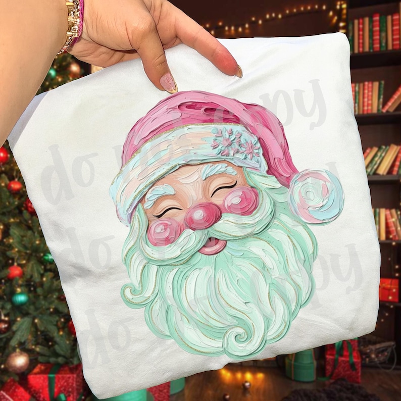 May include: White pillow with a colorful illustration of Santa Claus. Santa has a pink hat and rosy cheeks, with a long, mint green beard. The pillow is held by a person.