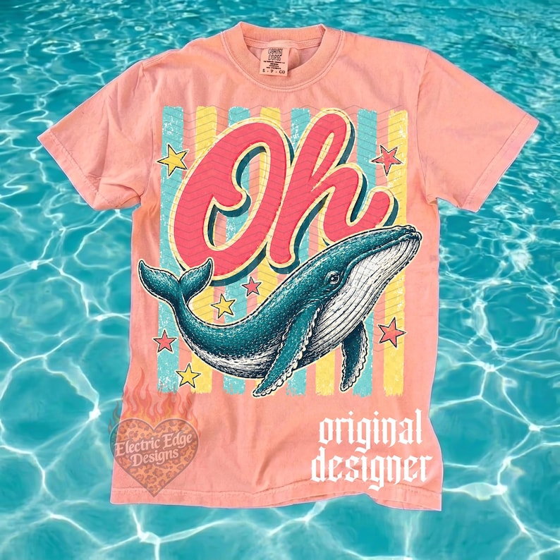 May include: A coral-colored t-shirt featuring a teal whale illustration with the word "Oh" in a retro font. The design includes yellow and blue stripes, star accents, and the text "original designer".
