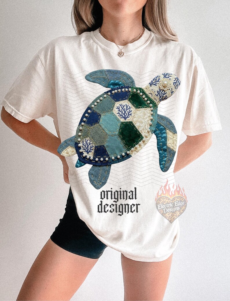 May include: Cream-colored t-shirt featuring a patchwork turtle design in shades of blue and green, embellished with pearls. The shirt has the text "original designer" and a logo with the text "Electric Edge Designs".