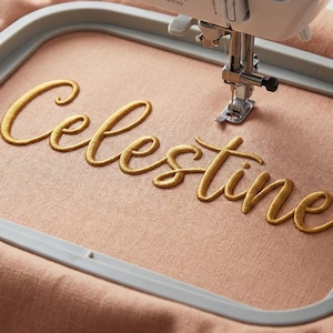 Celestine embroidery font stitched on fabric with an embroidery machine hoop showing machine embroidery in action, 3D puff/cursive style letters, high quality embroidery design created for embroidery machines including BX format, PES DST JEF and other multi-format embroidery files, perfect for embroidery alphabet projects, personalized hats, bags, tee shirts and craft DIY embroidery enthusiasts