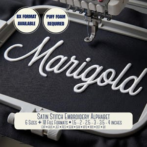 May include: A satin stitch embroidery alphabet design featuring the word Marigold in white thread on black fabric within an embroidery hoop. Text includes BX FORMAT AVAILABLE, PUFF FOAM REQUIRED, and 6 SIZES 1.5-2-2.5-3-3.5-4 INCHES.