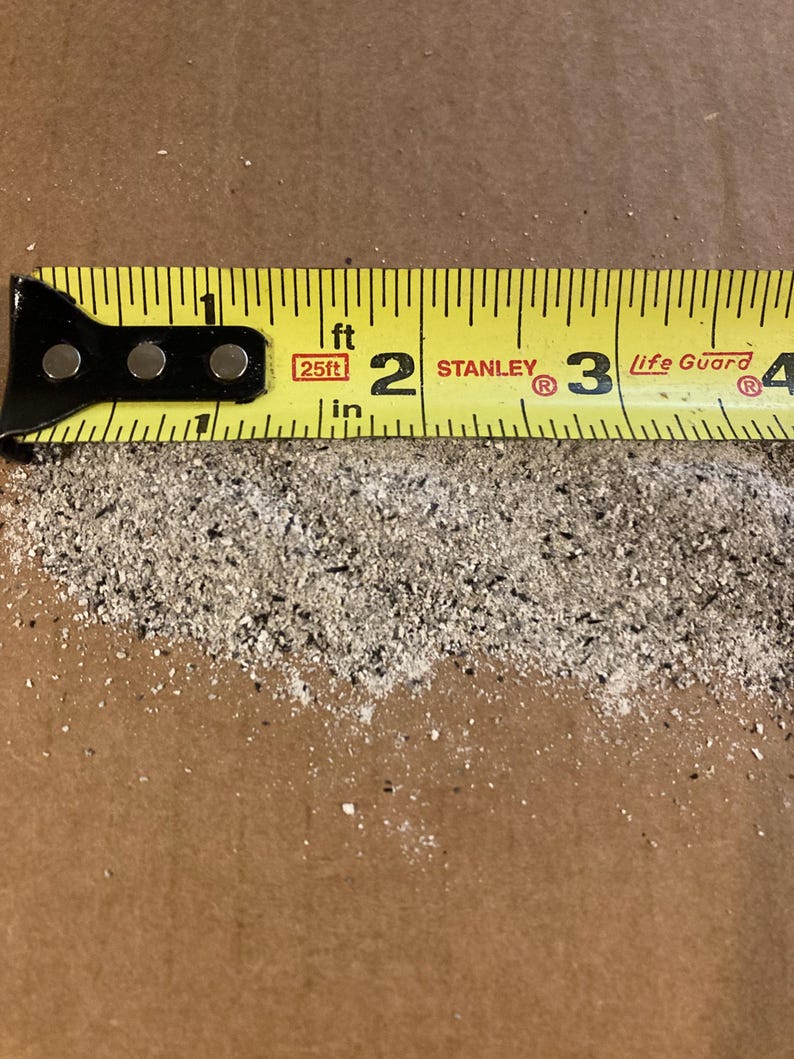 May include: A yellow measuring tape with black markings and a red label that says "25ft" is placed on a brown surface. The tape reads "1 ft 2 STANLEY 3 Life Guard 4".