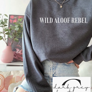 May include: A dark grey heather sweatshirt with the text "WILD ALOOF REBEL" printed in white on the front.