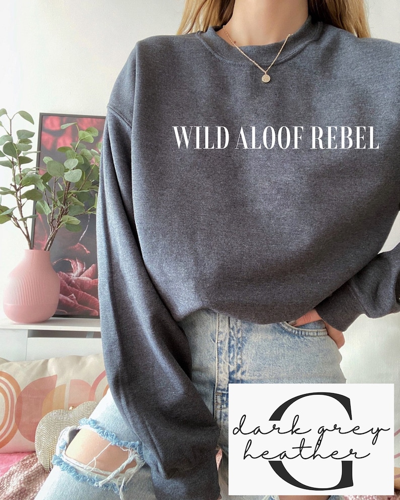 May include: A dark grey heather sweatshirt with the text "WILD ALOOF REBEL" printed in white on the front.