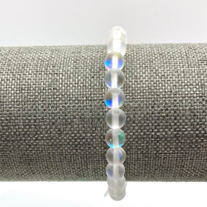 May include: A white beaded bracelet with iridescent rainbow-colored beads.