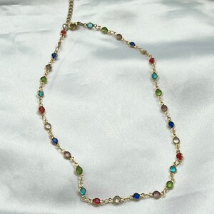 Puede incluir: Un collar de cadena dorada con cuentas redondas de colores. Las cuentas est&aacute;n en un patr&oacute;n de arco&iacute;ris.