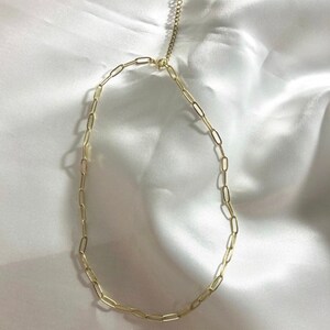 Puede incluir: Un collar de cadena dorada con un cierre en forma de coraz&oacute;n. La cadena est&aacute; hecha de peque&ntilde;as formas ovaladas enlazadas.