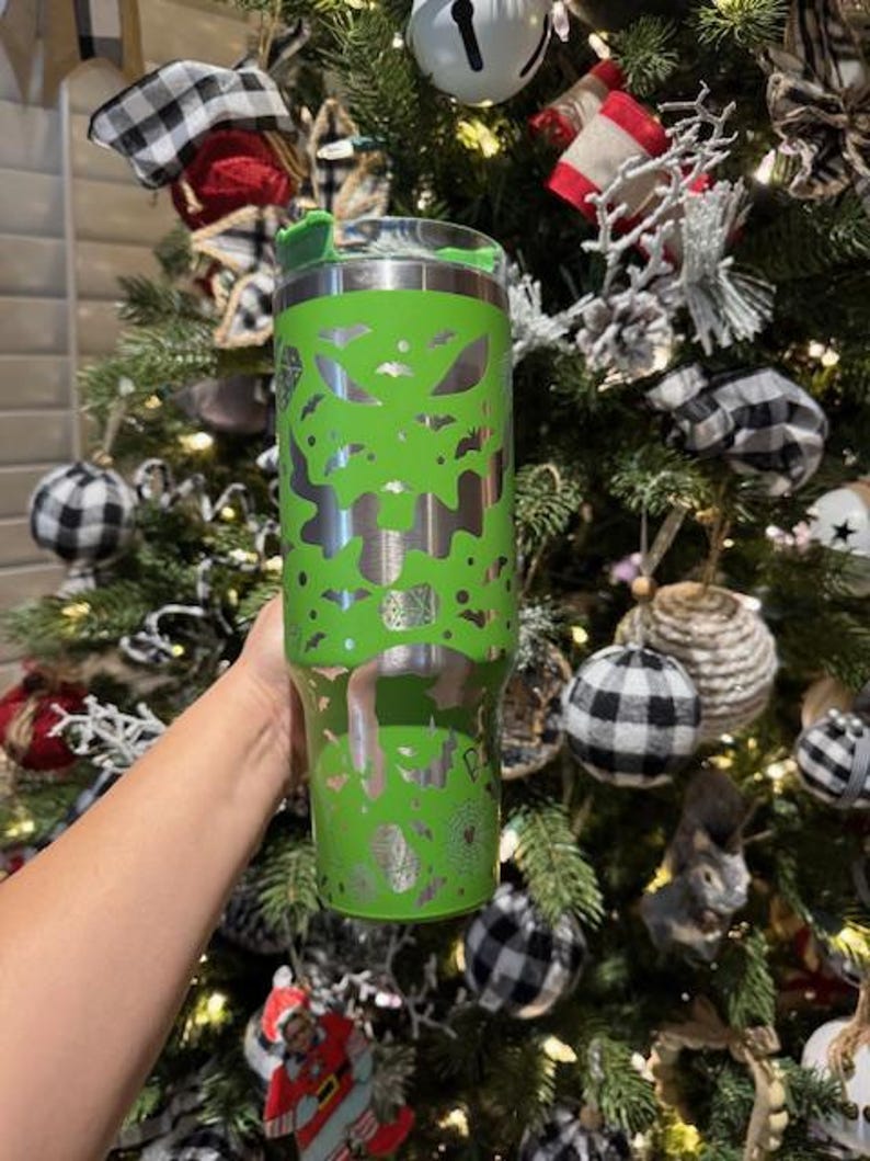 May include: A green stainless steel tumbler with a silver design of bats and ghosts. The tumbler has a lid with a straw hole.