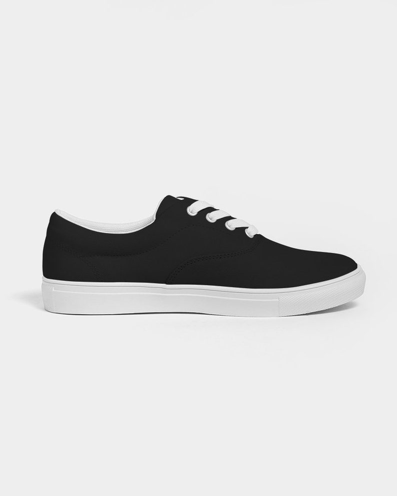 May include: Black canvas low-top trainers with white laces and a white rubber sole.