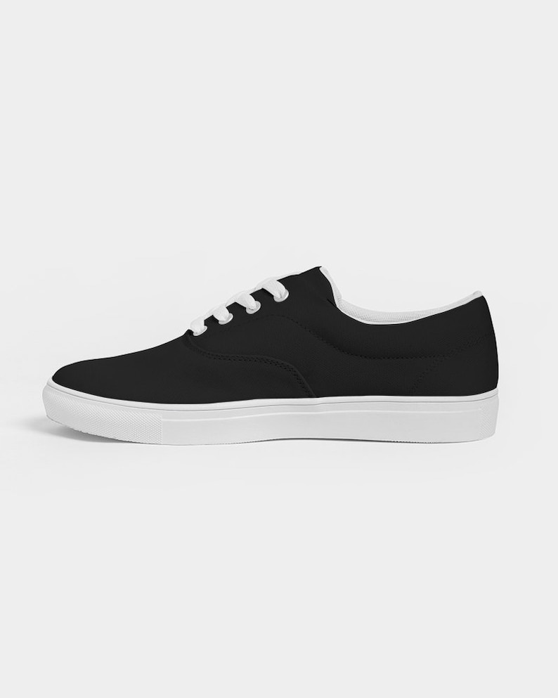 May include: Black canvas low-top trainers with white laces and a white sole.