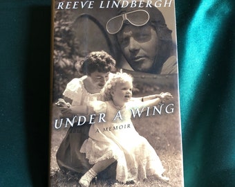 May include: Book cover with a black and white photo of a woman and a young child. The title of the book is "Under a Wing: A Memoir" by Reeve Lindbergh.