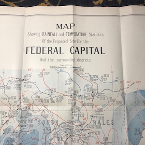 May include: A black and white map showing rainfall and temperature statistics for the proposed site of the Federal Capital and surrounding districts in Australia. The map includes lines and numbers indicating rainfall and temperature data. The map is titled "MAP Showing RAINFALL and TEMPERATURE Statistics Of the Proposed Site for the FEDERAL CAPITAL And the surrounding districts."