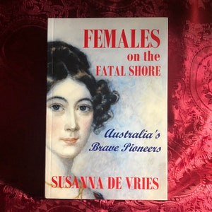 May include: Book cover featuring a portrait of a woman with dark hair and a white dress. The title is "Females on the Fatal Shore: Australia's Brave Pioneers" by Susanna de Vries.