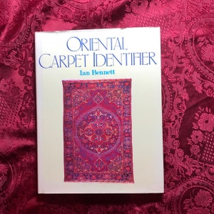 May include: A book titled "Oriental Carpet Identifier" by Ian Bennett. The cover features a colorful, intricate Persian rug with a central medallion.