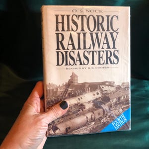 May include: A book titled "Historic Railway Disasters" by O.S. Nock, revised by B.K. Cooper. The book cover features a black and white photo of a train wreck with a blue sticker that says "Fourth Edition".
