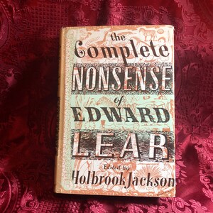 May include: A vintage book titled "The Complete Nonsense of Edward Lear" with a brown and white cover featuring illustrations of animals and a decorative border. The book is edited by Holbrook Jackson.
