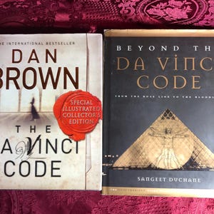 Pode incluir: Dois livros são exibidos. Um é "The Da Vinci Code" de Dan Brown, com um selo vermelho que diz "Special Illustrated Collector's Edition". O outro livro é "Beyond the Da Vinci Code".