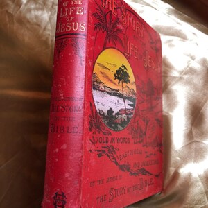 May include: Red hardcover book titled "The Story of the Life of Jesus" with a sunset scene on the cover. The book is written in simple words for easy reading and understanding. It is by the author of "The Story of the Bible."