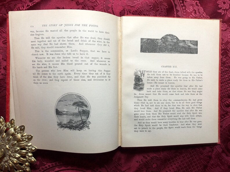 May include: An open book with a red cover and white pages. The book is titled "The Story of Jesus for the Young." The pages contain text and illustrations. The book is open to a page with the title "Chapter XXI." The text on the page describes Jesus talking to his apostles.