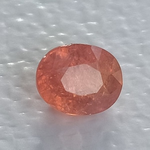 May include: A light pink oval-shaped gemstone with a faceted cut.