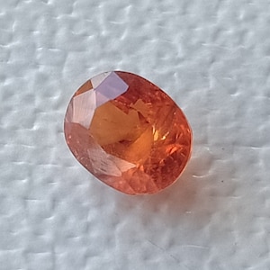 May include: A bright orange oval-shaped gemstone with a faceted cut.