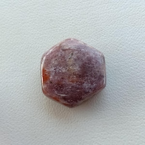 May include: A hexagonal shaped, polished, pink and orange gemstone with white inclusions.