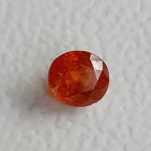 May include: A bright orange oval-shaped gemstone with a faceted cut.