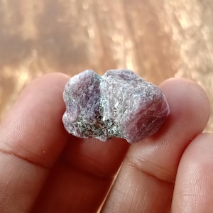 May include: A cluster of rough pink and grey ruby crystals with a silvery sheen.