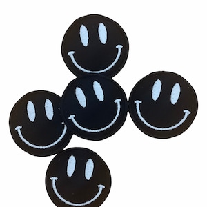 May include: Five black embroidered smiley face patches with white stitching.