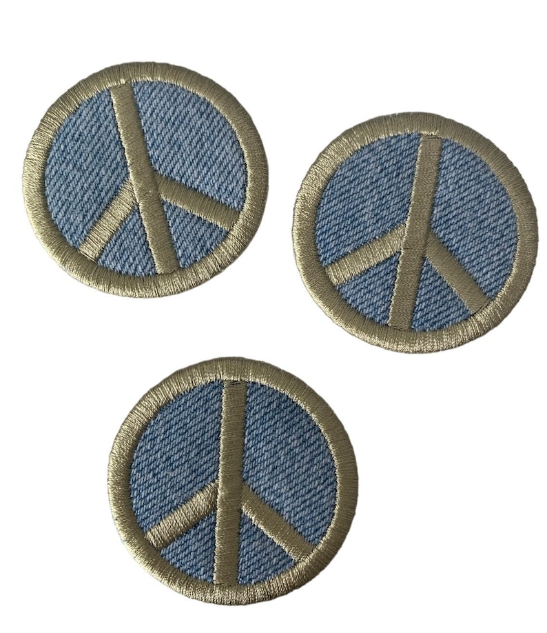 May include: Three denim peace sign patches with a beige outline. The patches are circular and have a textured denim fabric.