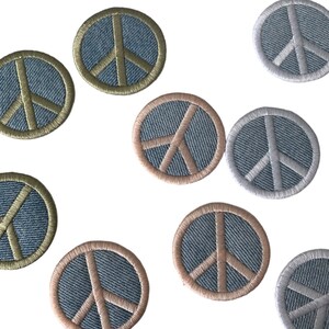 May include: Nine embroidered peace sign patches in various colors. The patches are circular and feature a peace sign design with a denim background.