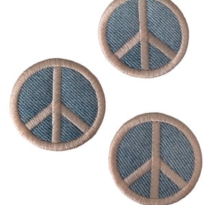May include: Three denim peace sign patches with a light brown outline. The patches are round and have a textured denim fabric.